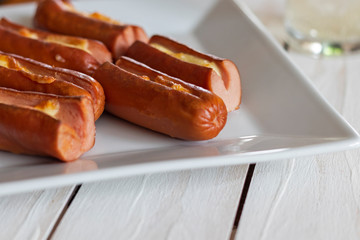 Roasted sausage with yellow cheese over white wooden background