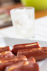 Roasted sausage with yellow cheese and a glass of soda over white wooden background