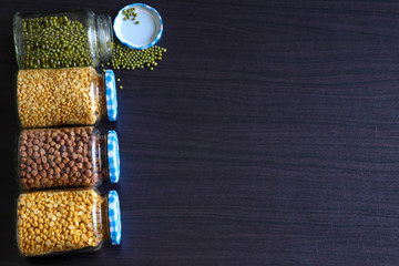 bottles filled with grains laying on a dark wooden background