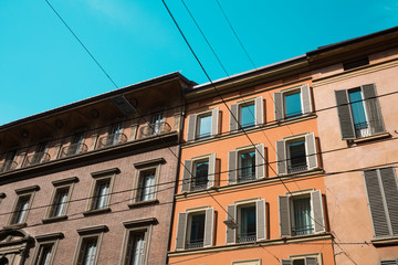 Fototapeta na wymiar orange, pink apartment with windows, shutters, balcony in Bologna, Italy. Against blue sky