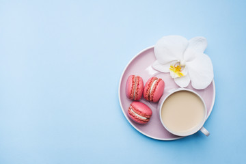 Concept morning Breakfast. Cup of coffee macaroon cookies on blue pastel background. Flat lay style.