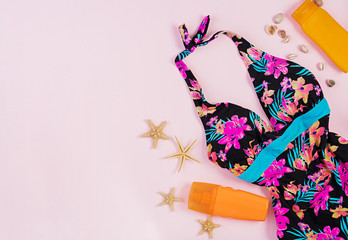 Swimsuit with different seashells and starfish on pink background. Top view