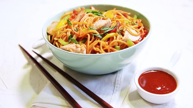 Chicken Hakka/Schezwan noodles footage / video, served in a bowl with chopsticks. selective focus