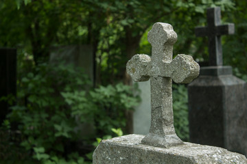 Old grave with cross on tombstone traditional European cemetery. Aged grave yard in forest