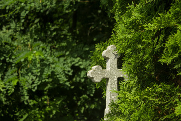 Old grave with cross on tombstone traditional European cemetery. Aged grave yard in forest