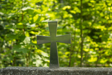 Old grave with cross on tombstone traditional European cemetery. Aged grave yard in forest