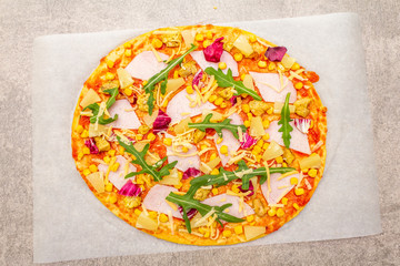 Raw Hawaiian pizza on parchment on stone background, top view