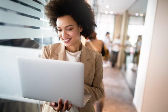 Portrait of an attractive young african businesswoman smiling while standing by windows in office