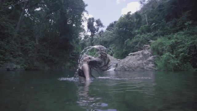 SLOW MOTION: girl flips her hair, full of water, in front of Mango Waterfall in Adjuntas, Puerto Rico.