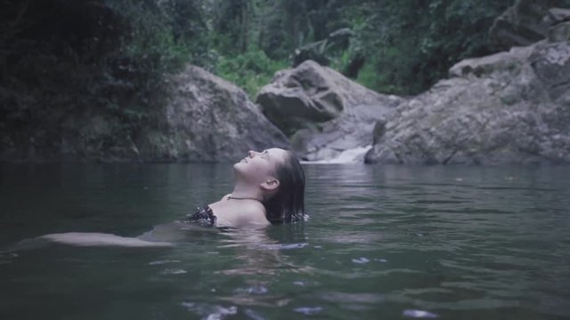 SLOW MOTION: girl slowly lifts her head out of the water found at the base of Mango Waterfall in Adjuntas, Puerto Rico.