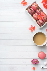 Cup of coffee, macaroon cookies in a box, flowers on a white background. copy space. concept beautiful Breakfast. flat lay