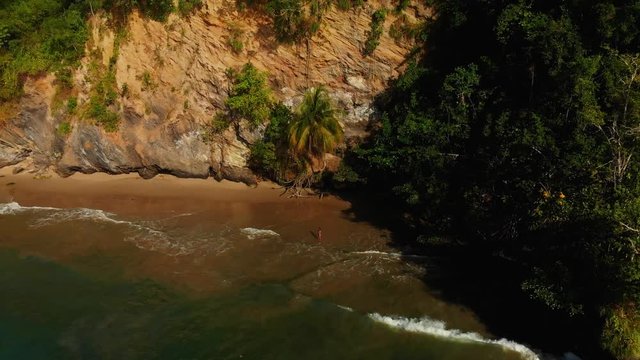 Aerial view of bikini model at a cliff-side beach enjoying the waves