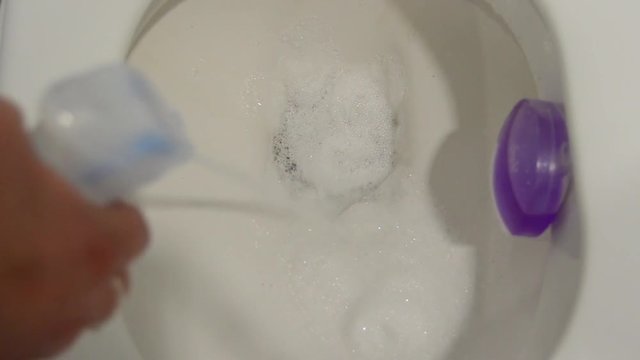 Woman hand spraying toilet bowl to be washed.