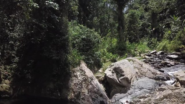 AERIAL: lifting up from a girl touching her feet to the base of Mango Waterfall in Adjuntas, Puerto Rico.