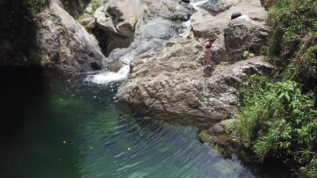 AERIAL: slight movements while watching a girl on a rocky structure that makes up the Mango Waterfall in Adjuntas, Puerto Rico