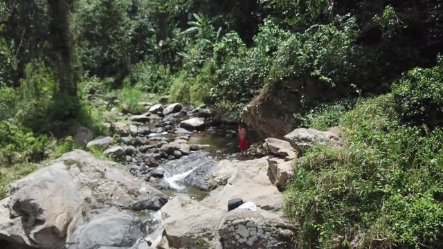 AERIAL: pulling away and behind some trees to hide the magical scenery of Mango Waterfall in Adjuntas, Puerto Rico.