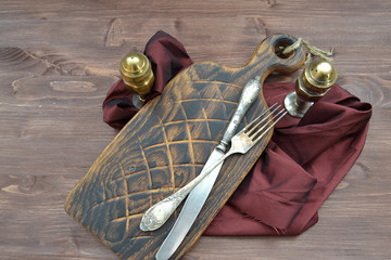 Obraz premium Red wood cutting board with silver pepperbox and fork on dark background. Brown shabby wooden table. Concept of healthy diet.