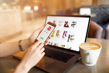 Women hands using smartphone and laptop computer for online shopping. Payment Detail page display.