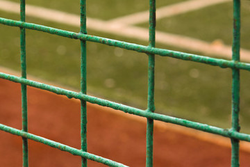 Open football field behind the fence. Focus on the fence. Shallow depth of field