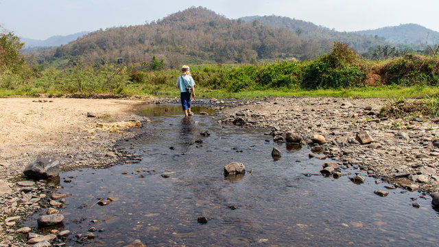Young boy walking in a shallow river bed in Thailand
