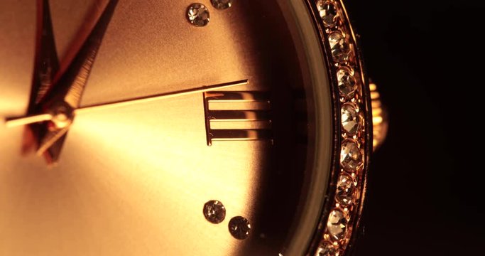 Macro close-up on the roman numeral 3 on a diamond-studded, gold watch.