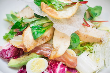 Portion of salad with grilled chicken, bacon, vegetable leaves