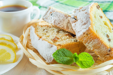 Sliced biscuit cake, a cup of tea, lemon slices and mint leaves. Delicious breakfast or dessert.