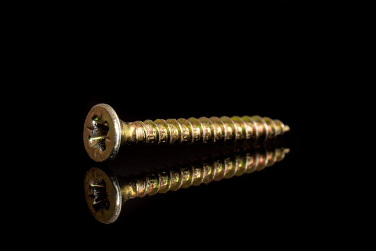 Closeup of one whole golden screw work item isolated on black glass