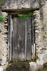 old wooden door in rock wall, part of hiking path Valle delle Ferriere, Italy