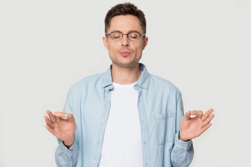 Caucasian man in glasses isolated in studio meditating