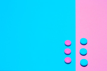 Pink and blue pills isolated on bicolor pink and blue colored background. Medication and prescription pills minimal flat lay with copy space.