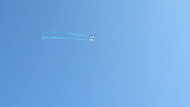 Kite that looks like a butterfly soaring high in the sky; footage representing freedom, hope, innocence, childhood, fun, summertime, play time, worry free.