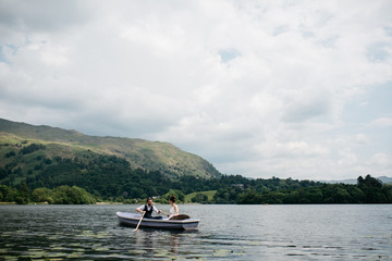 Fototapeta na wymiar Bride and groom rowing a boat on a lake