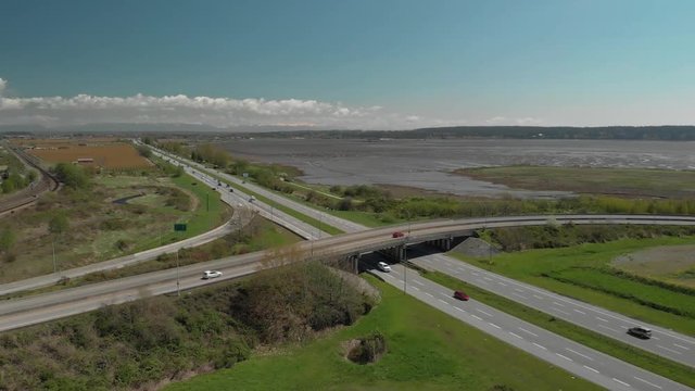 Aerial video of highway with cars moving in slow motion with ocean in the background.