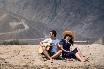 Couple singing and playing guitar buy the beach