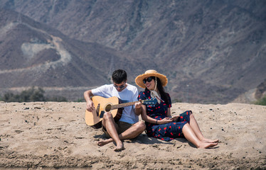 Couple singing and playing guitar buy the beach