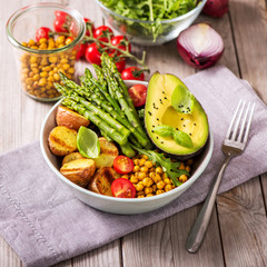 Healthy dinner with green asparagus, lentils and spicy chickpeas, avocado, arugula, vegan,...