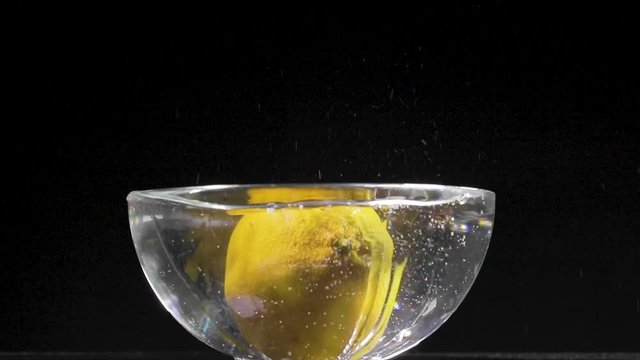 Limone intero che cade in una bacinella piena d'acqua e schizza al rallentatore. 