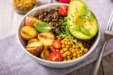 Buddha bowl with baked potatoes, lentils and spicy chickpeas, avocado, arugula, vegan, vegetarian healthy dinner