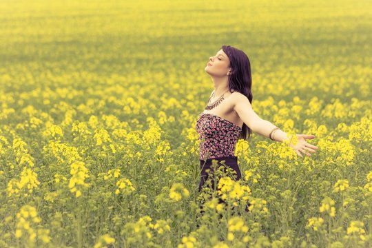 Happy beautiful woman in free summer love of youth wellbeing. Attractive young beauty girl enjoying the warm sunny sun in nature rapeseed field takes time feeling sustainability and contemplation