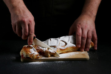 chef slices a pie on dark background. pie making concept. recipe of pie or cake