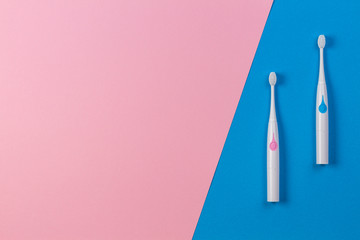 Two toothbrushes on blue and pink background. Top view