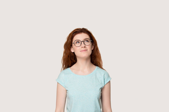 Dreamy redhead girl in glasses look up imagining