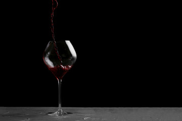 red wine pouring in glass isolated on black