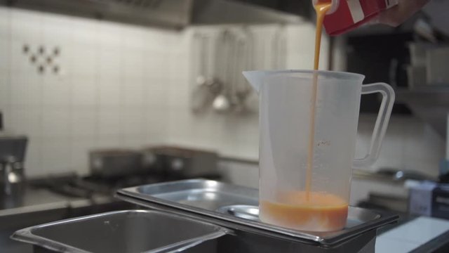 Cook In A Kitchen Pouring Pasteurized Egg Yolk In A Dozing  Plastic Yug
