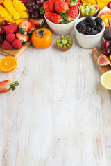 Healthy raw fruits background, cut mango, strawberries raspberries oranges plums apples kiwis grapes blueberries cherries, on white table, copy space, top view, selective focus