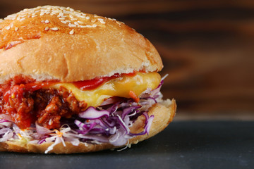 burger with coleslaw and cheese on wood and fries. authentic homemade burger with