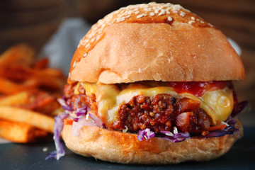 burger with cheese and vegetable and fries on rustic background