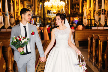 the newlyweds hold hands and leave the church after the ceremony