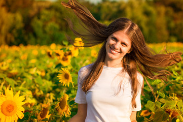 Summer portrait of happy young woman in white with flying hair in field
